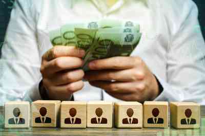 Figuren auf Würfeln und Hände mit Geldscheinen - © Andrii Yalanskyi - Adobe Stock.com